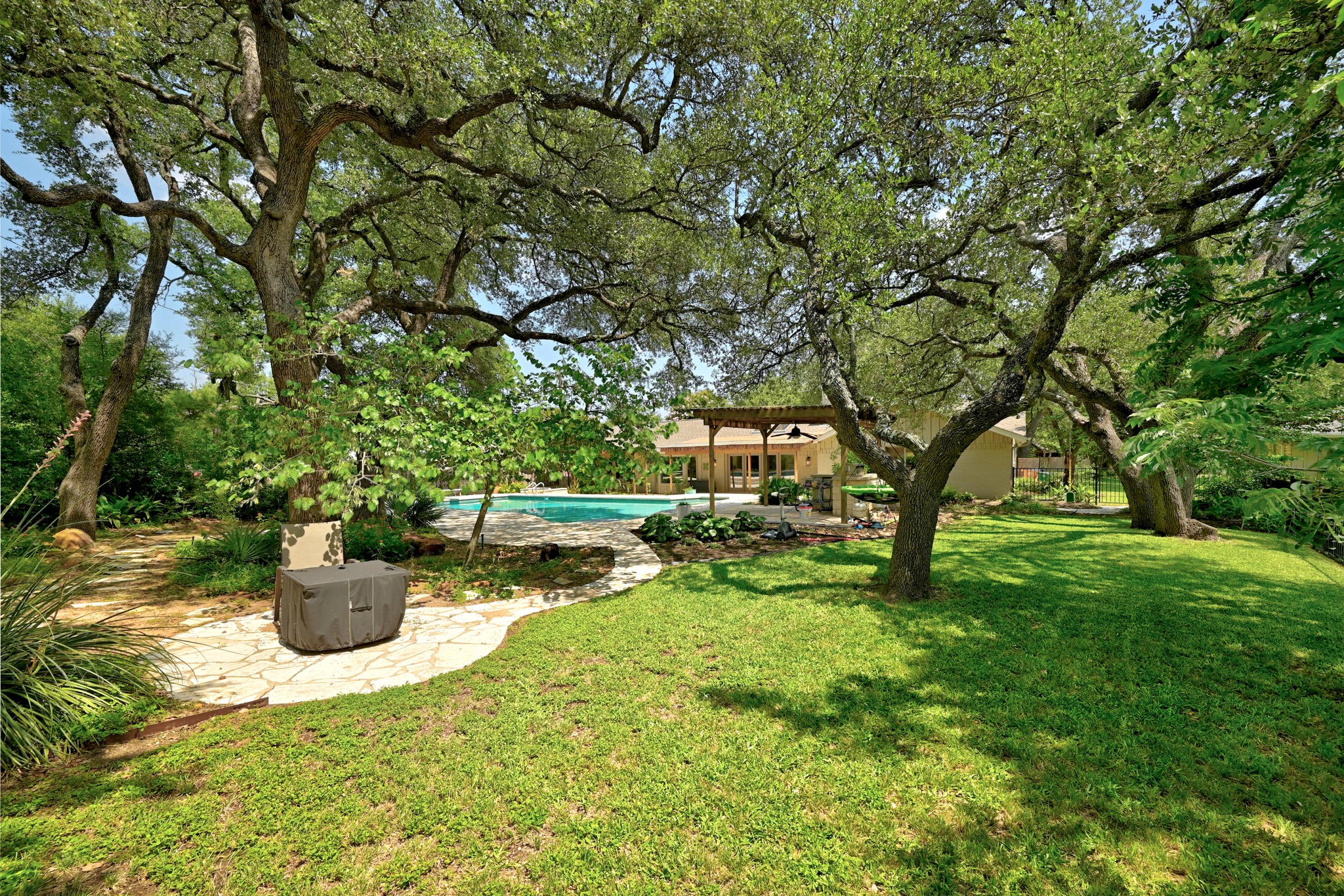 8608 Crest Ridge Circle Austin, TX 78750 - Photo 34 of 38 A private, tree-shaded backyard sanctuary with a glistening pool and a stone pathway.