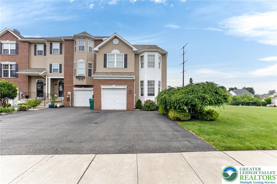 5440 Spring Ridge Drive West Macungie, PA 18062 - Photo 1 of 40 A welcoming townhome exterior with attached garage, paved driveway, and vibrant green landscaping.