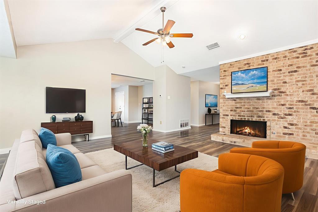 229 South Heartz Road Coppell, TX 75019 - Photo 4 of 19 Virtually staged.Living area with beam ceiling, wood finished floors, a ceiling fan, a fireplace, and high vaulted ceiling