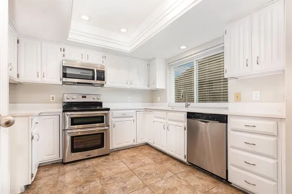 a kitchen with kitchen island a refrigerator stove and white cabinets