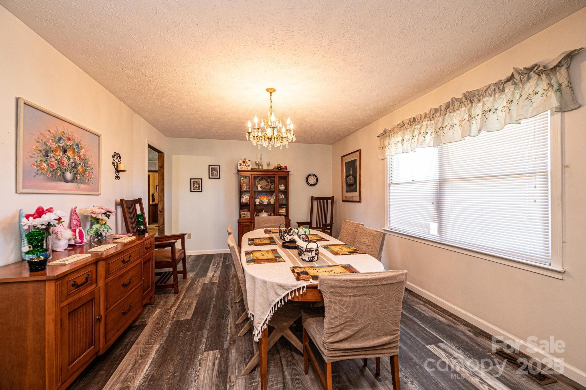 1221 Connelly Springs Road Lenoir, NC 28645 - Photo 17 of 42 a view of a dining room with furniture a chandelier and wooden floor