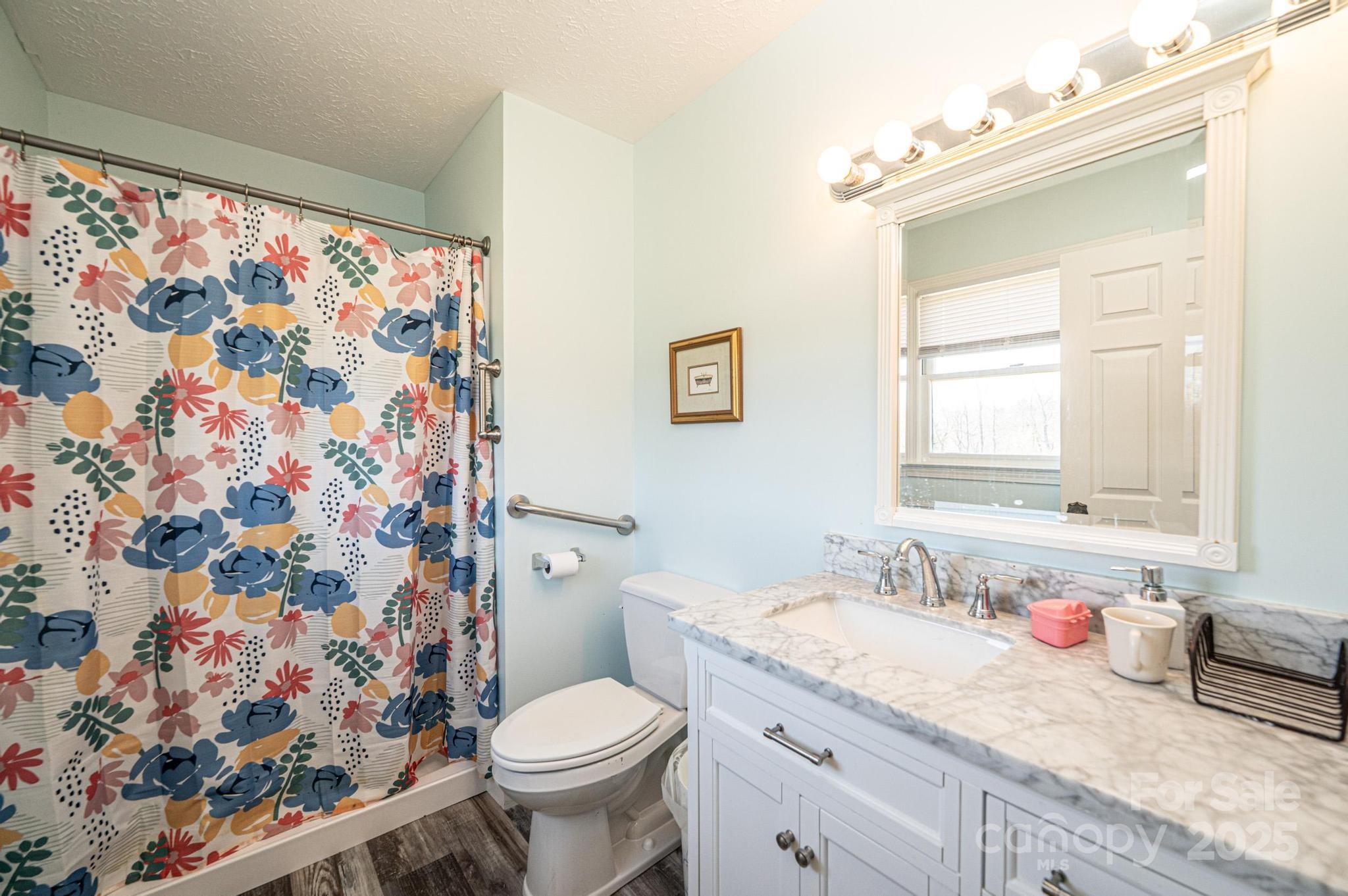 1221 Connelly Springs Road Lenoir, NC 28645 - Photo 20 of 42 a bathroom with a granite countertop sink mirror vanity and toilet