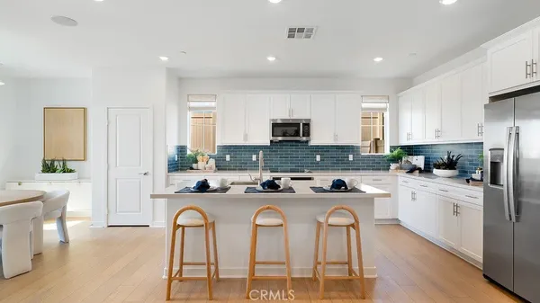 a kitchen with stainless steel appliances granite countertop a stove a sink a refrigerator a dining table and chairs