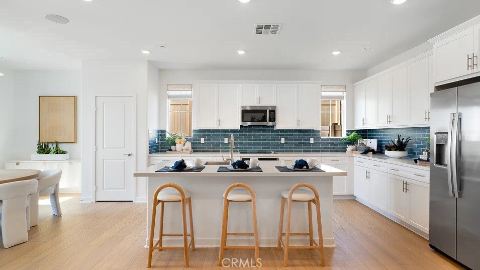 a kitchen with stainless steel appliances granite countertop a stove a sink a refrigerator a dining table and chairs