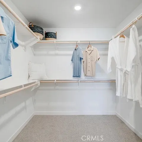 a view of walk in closet with clothes and shoes