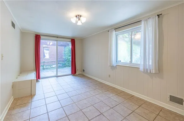 a view of an empty room with window and chandelier fan