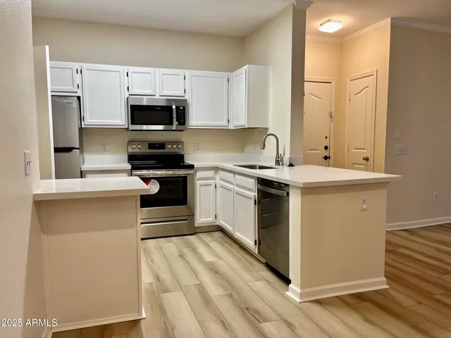 a kitchen with stainless steel appliances granite countertop a stove top oven a sink dishwasher and a refrigerator with wooden floor