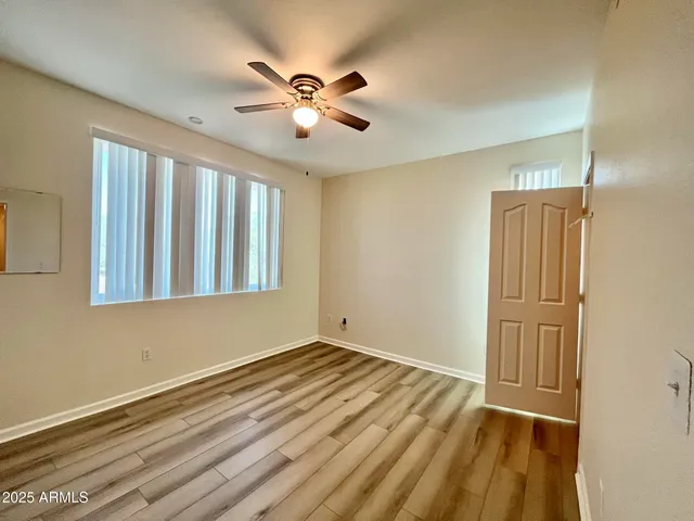 a view of an empty room with window and chandelier fan