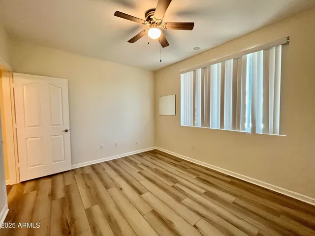 a view of an empty room with window and a ceiling fan