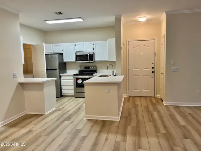 a kitchen with a sink a counter top space stainless steel appliances and cabinets