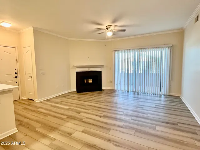 a view of an empty room with wooden floor fireplace and a window