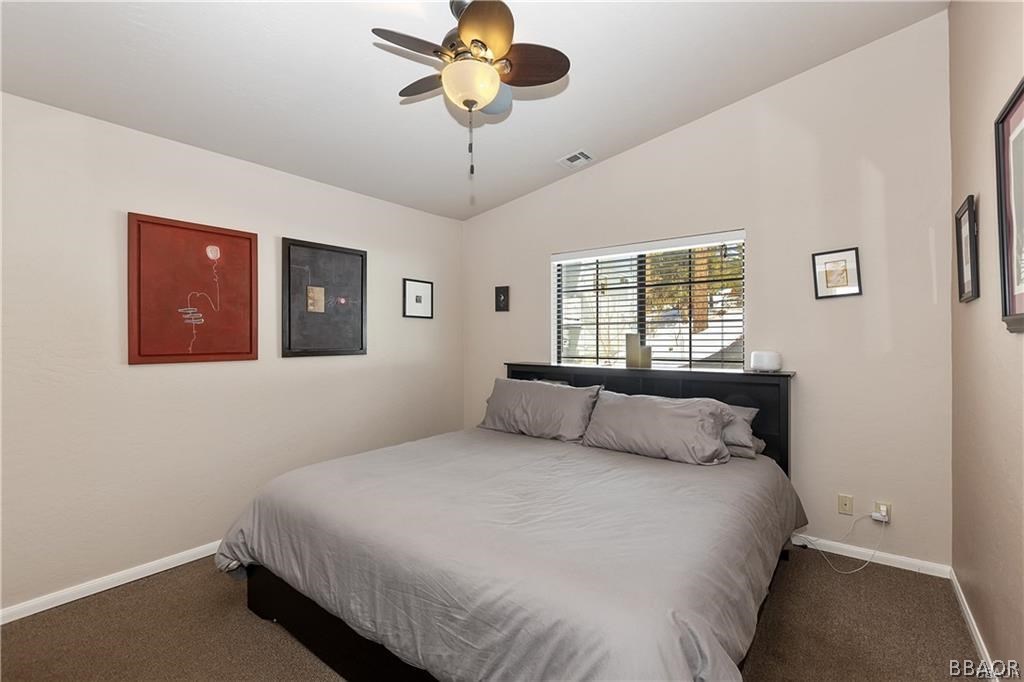 39665 Flicker Road Fawnskin, CA 92333 - Photo 16 of 29 a bedroom with a large bed and a chandelier