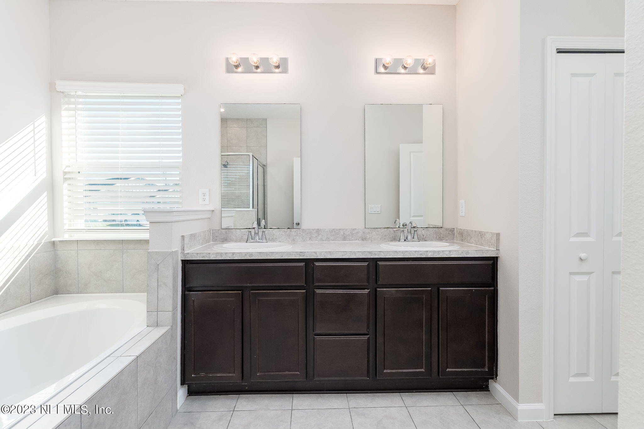 5556 Kellar Circle Jacksonville, FL 32218 - Photo 21 of 28 a bathroom with a tub a double vanity sink and mirror