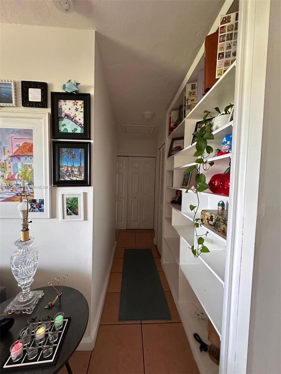 1021 Crystal Lake Drive, Unit 311 Deerfield Beach, FL 33064 - Photo 13 of 17 a hallway with painting on the wall and a potted plant