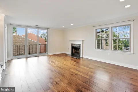 an empty room with wooden floor fireplace and windows