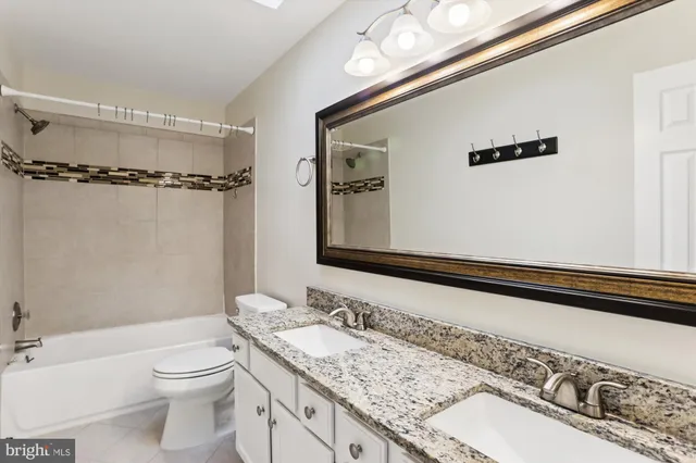 a bathroom with a granite countertop sink a toilet and shower