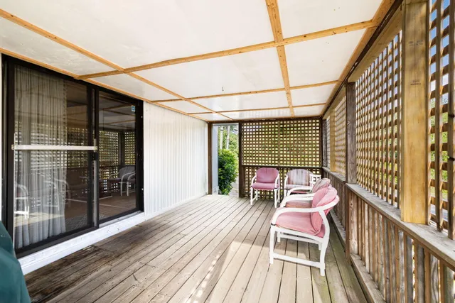 a balcony with wooden floor table and chairs