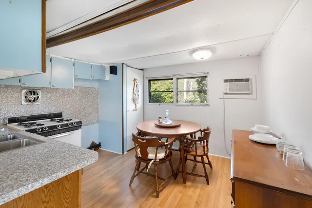 a kitchen with stainless steel appliances granite countertop a stove a refrigerator a kitchen island a dining table and chairs with wooden floor