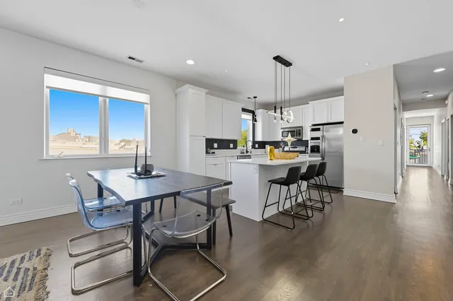 a kitchen with a dining table chairs and wooden floor
