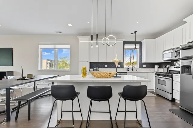 a kitchen with stainless steel appliances a stove a sink refrigerator and white cabinets next to a window