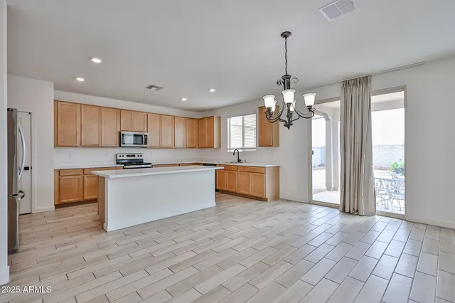 a large kitchen with granite countertop a stove a sink dishwasher a refrigerator and white cabinets with wooden floor