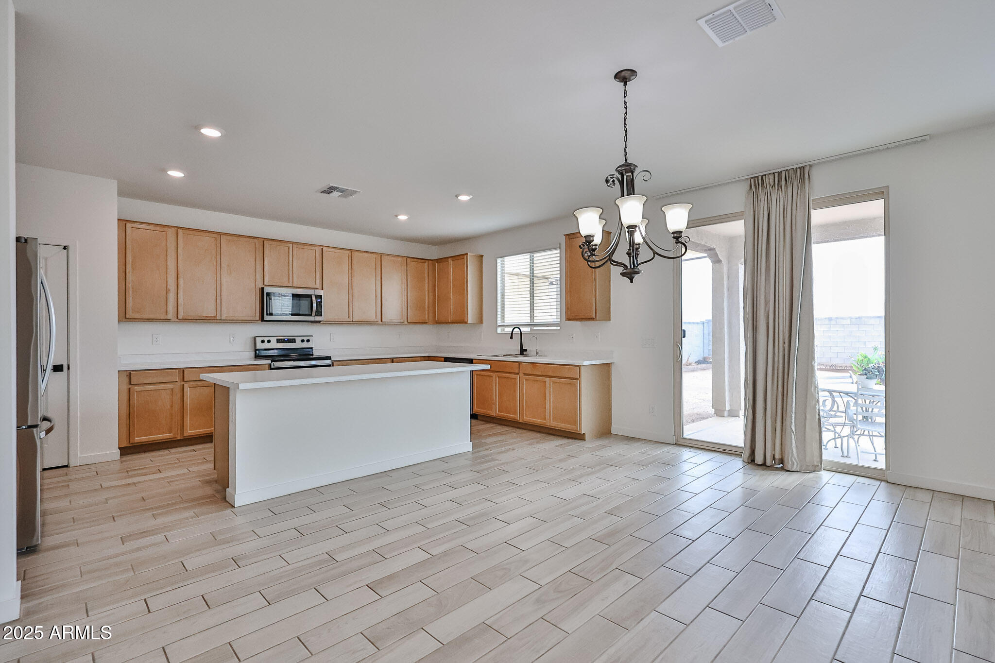 509 East Elm Lane Avondale, AZ 85323 - Photo 9 of 40 a large kitchen with granite countertop a stove a sink dishwasher a refrigerator and white cabinets with wooden floor