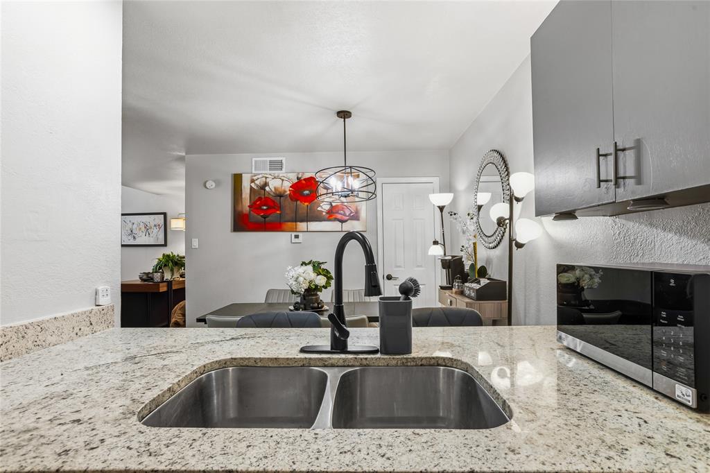 5540 Boca Raton Boulevard, Unit 181 Fort Worth, TX 76112 - Photo 7 of 21 Kitchen featuring light-toned countertops, a dual basin stainless steel sink with a matte black faucet, and an integrated microwave