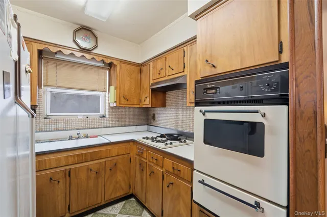 a living room with stainless steel appliances furniture and a kitchen view