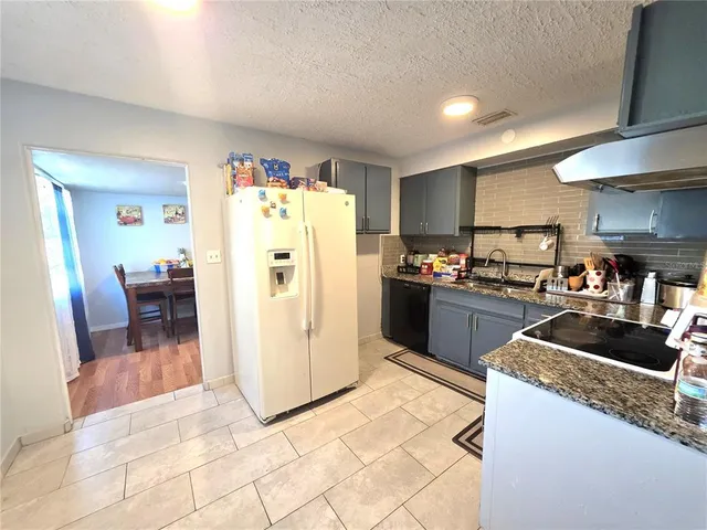 a kitchen with granite countertop a refrigerator and a sink