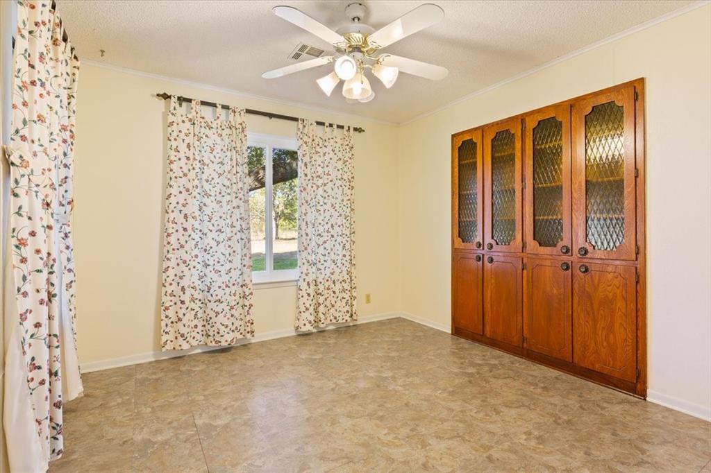 208 South Hedwig Street Riesel, TX 76682 - Photo 12 of 31 Unfurnished room with crown molding, a textured ceiling, and ceiling fan