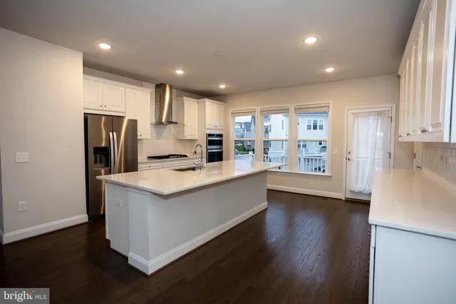 a view of an empty room with wooden floor and a chandelier