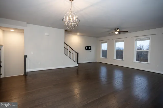 a view of an empty room with chandelier fan and fire place