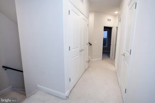 a view of a hallway with closet and a bathroom