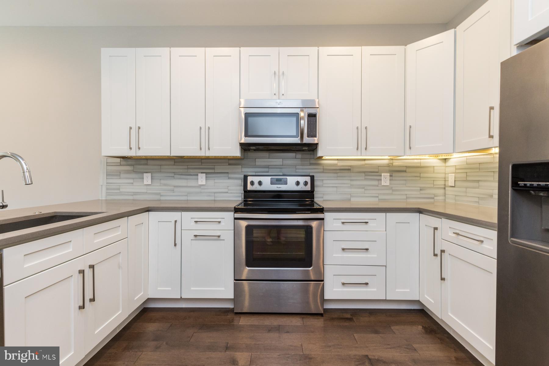 1815 Ranstead Street, Unit 1 Philadelphia, PA 19103 - Photo 5 of 27 a kitchen with white cabinets and stainless steel appliances
