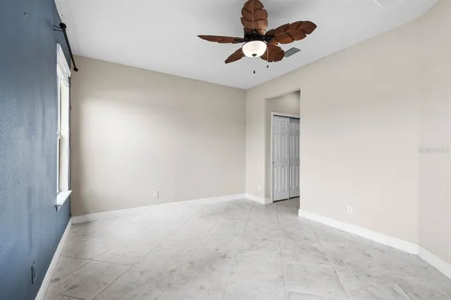 an empty room with a chandelier fan and windows