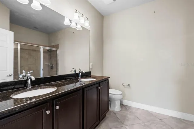 a bathroom with a granite countertop sink a toilet and a mirror
