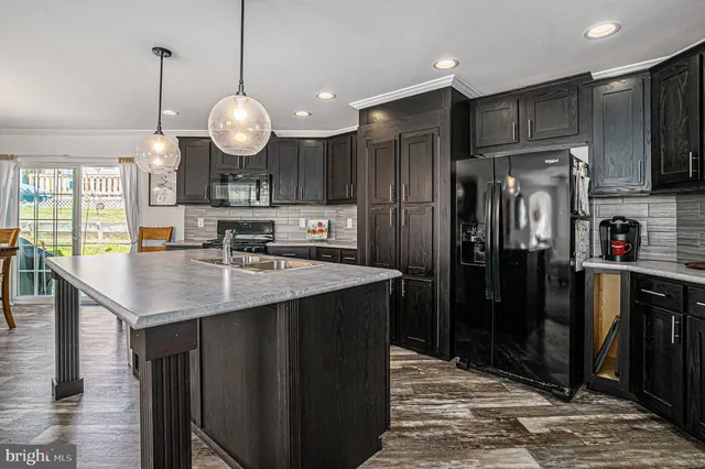 a kitchen with stainless steel appliances kitchen island granite countertop a refrigerator a stove and a sink with wooden floor