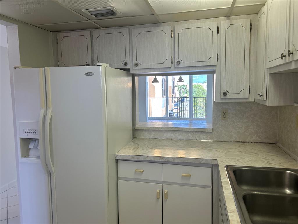 1855 West 60th Street, Unit 325 Hialeah, FL 33012 - Photo 11 of 18 a kitchen with granite countertop a refrigerator sink and cabinets