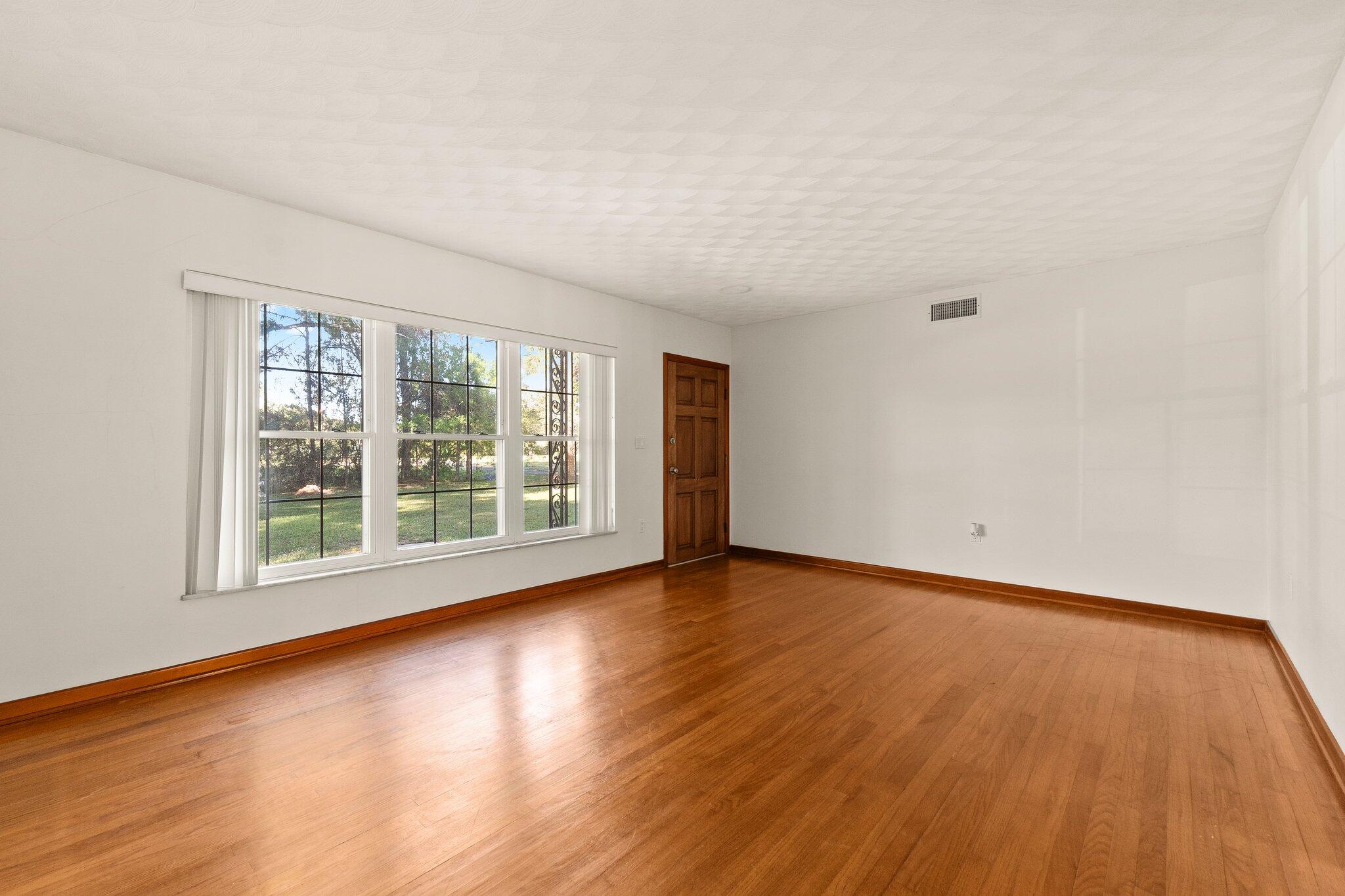 11541 Okeechobee Road Fort Pierce, FL 34945 - Photo 13 of 46 a view of an empty room with wooden floor and a window