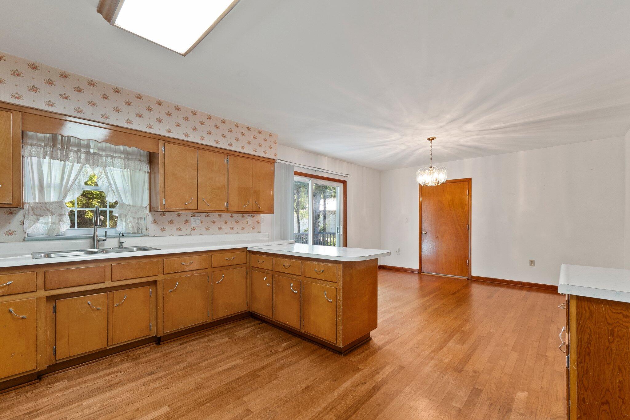 11541 Okeechobee Road Fort Pierce, FL 34945 - Photo 18 of 46 a large kitchen with stainless steel appliances granite countertop a sink and cabinets with wooden floor