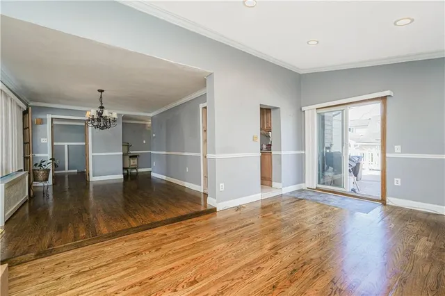 an empty room with wooden floor and dining room view