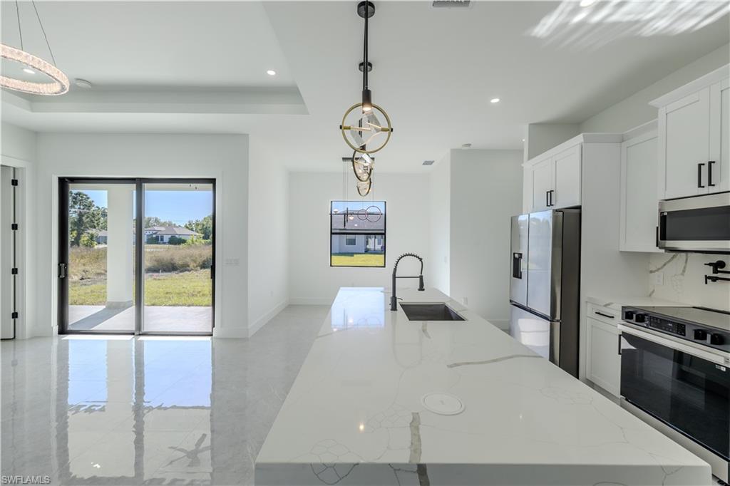 3303 24th Street Southwest Lehigh Acres, FL 33976 - Photo 19 of 25 a kitchen with stainless steel appliances granite countertop a refrigerator a stove and a sink with wooden floor