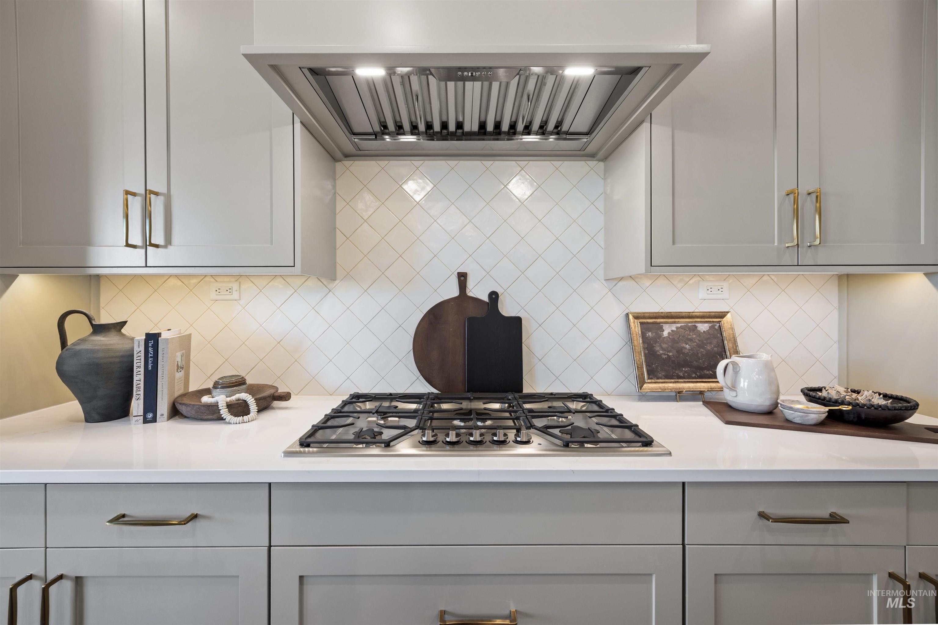 5847 South Pinpoint Way Meridian, ID 83642 - Photo 24 of 44 Kitchen with range hood, gray cabinets, stainless steel gas stovetop, decorative backsplash, and light stone countertops