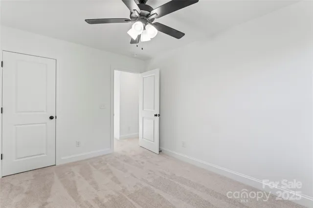 an empty room with a chandelier fan and closet area