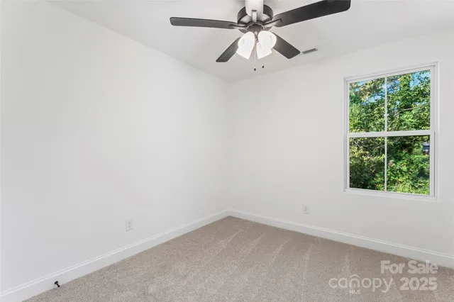 an empty room with a window and a fan