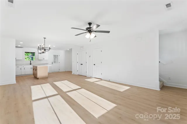 a view of a white room with a ceiling fan and window
