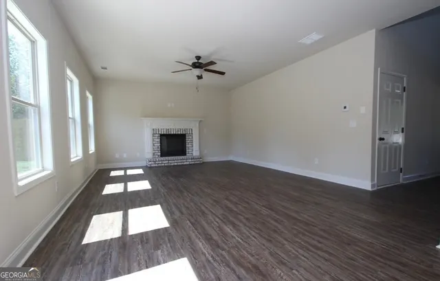 an empty room with wooden floor fan and windows