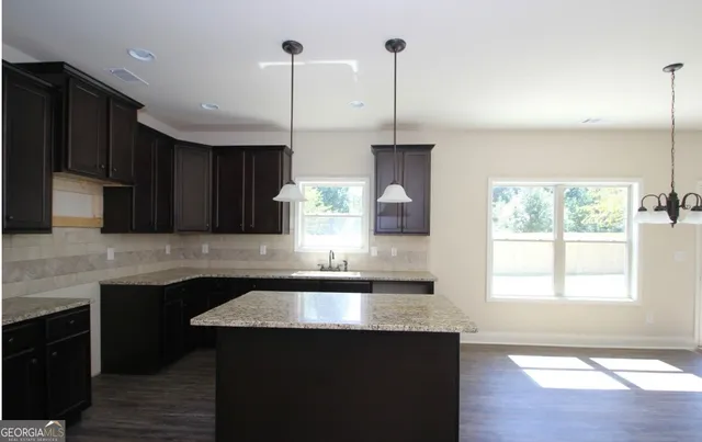 a kitchen with stainless steel appliances granite countertop a sink a stove a kitchen island and windows