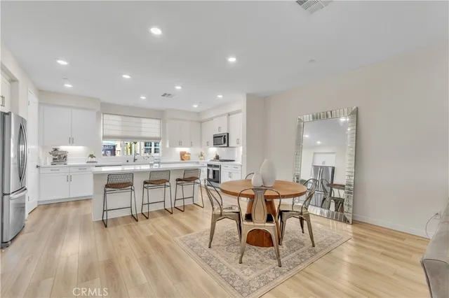 a kitchen with stainless steel appliances a sink a stove a refrigerator cabinets and a dining table