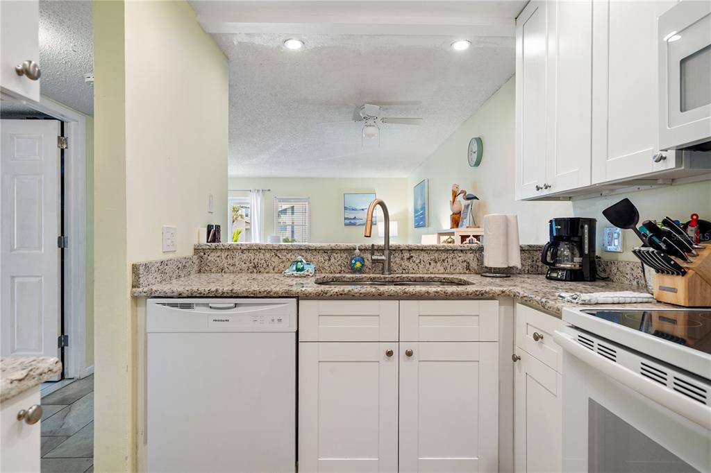 230 Medallion Boulevard, Unit E Madeira Beach, FL 33708 - Photo 10 of 35 a kitchen with granite countertop white cabinets and a sink